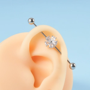 Industrial barbell earring with a crystal flower design on a silicone ear model