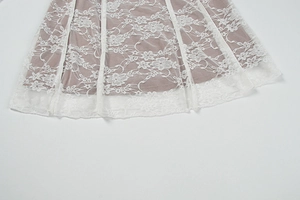Detailopname van witte bloemenkant aan de zoom met een zachte pastelkleurige voering