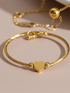 Macro detail of 18k gold plated stainless steel heart charm on a twisted cable bangle