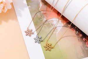 Detailed view of snowflake pendant necklaces in gold, silver, and rose gold finishes