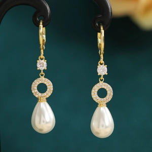 Detail of drop earrings with gold metal, zircon accents and teardrop pearls
