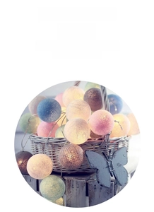 Close-up of pastel cotton ball LED string lights in a woven basket for home decor