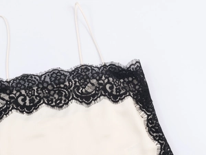 Detailed view of black lace trim and satin fabric on white camisole top for women