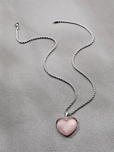 Detail of pink heart-shaped crystal pendant on a silver-tone twisted rope chain
