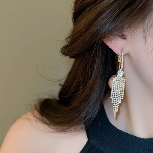 Macro shot of long gold tassel earrings with sparkling rhinestones and a round centerpiece