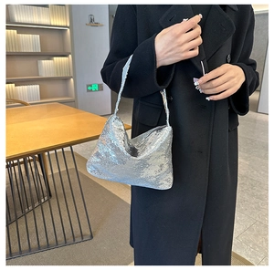 Détail d'un sac à main pailleté argenté tenu par un mannequin en manteau noir