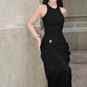 Gros plan sur la robe mi-longue noire avec boucle en métal et détails de plissés