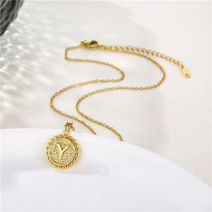 Detailed close-up of golden round pendant necklace featuring letter Y on ceramic plate