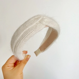 Close-up of a white plush knit headband featuring a stylish central knot design