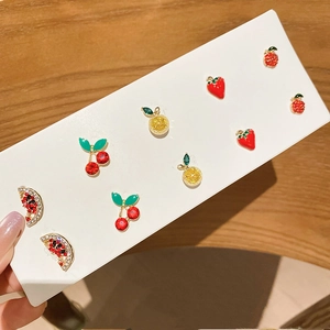 Detailed view of five pairs of colorful rhinestone fruit earrings on a white display card