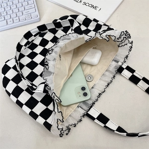 Detailed view of checkered tote bag with lace trim and internal organizer compartments
