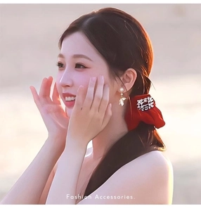 Detailed close-up of pearl wing earrings and a red velvet bow with rhinestone accents