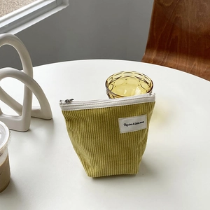 Detail of yellow-green corduroy makeup pouch featuring a zipper and Big star text label