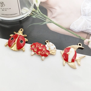 Tre ciondoli smaltati rosso e oro a forma di coccinella, pecora e pesce per gioielli