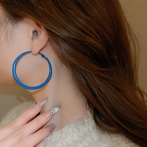 Close-up of a model wearing a large Klein blue matte round hoop earring for women