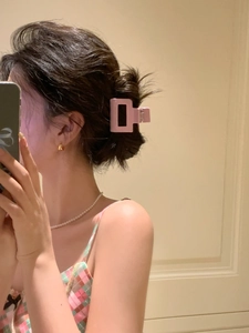 Pink matte square hair claw clip styled on a woman's half-up bun for hair accessory detail