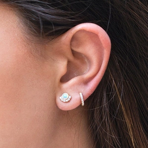 Elegant gold earrings with opal stones and pavé cubic zirconia shown on model's ear