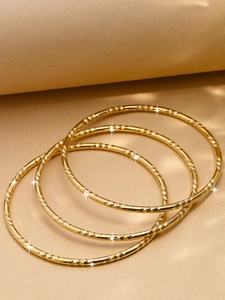 Détail de quatre bracelets dorés de 3mm avec textures en spirale et finitions polies