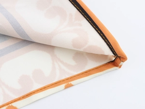 Close-up of orange stitched hem on coconut tree print dress with cotton linen texture