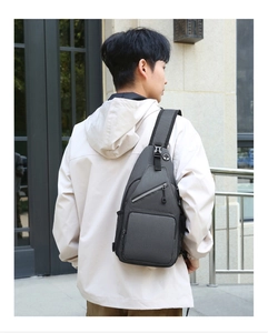 Detail of grey crossbody bag with adjustable strap and multi-pocket design on male model