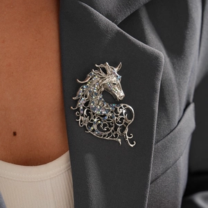 Close-up of a vintage horse brooch with colorful crystals on a grey suit lapel