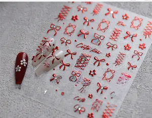 Macro detail of red metallic bow nail stickers and ribbon decals on a textured stone surface