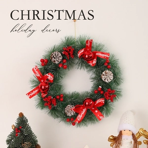 Christmas wreath with green pine needles, red berries and pinecones on a light wall