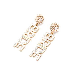 Macro detail of gold BRIDE earrings with white enamel finish and elegant faux pearls
