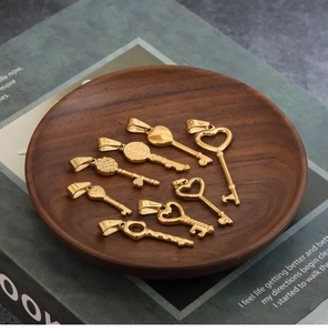 Detailed view of eight vintage gold heart-shaped key pendants on a wooden tray
