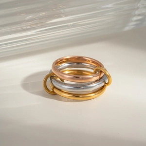 Close-up of three interlocking rings in gold, silver, and rose gold with polished finish
