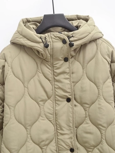 Detail of khaki quilted padded coat with hood and black buttons hanging on white background