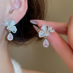 Macro detail of silver butterfly earrings with pink drop-shaped zircon and mother of pearl