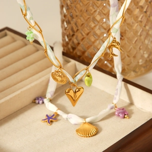 Collier foulard en soie avec breloques cœur doré et coquillage dans un écrin à bijoux