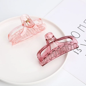 Pink and purple acrylic shark hair clips with golden metal springs in a white ceramic bowl
