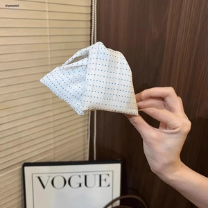 Close-up of a white and blue polka dot fabric hair claw clip held in hand with Vogue decor
