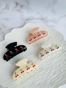 Detail of four acetate hair claws with sparkling cherry rhinestone patterns in mixed colors