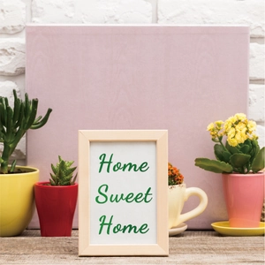 Minimalist natural wood picture frame with green Home Sweet Home text on a white desk