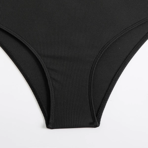 Macro shot of black ribbed swimsuit fabric detail showing high-quality stitching and texture