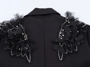 Gros plan détaillé des broderies de perles sur l'épaule de cette robe noire chic
