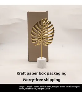 Detailed view of golden monstera leaf metal ornament on a white marble cylindrical base