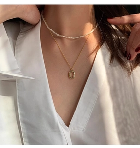 Detail of S925 engraved irregular gold pendant on a layered pearl necklace