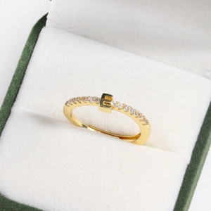 Macro detail of 18k gold plated letter E ring with small diamonds in a green jewelry box