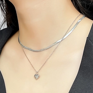 Detail view of double-layered silver snake chain necklace featuring a polished heart pendant