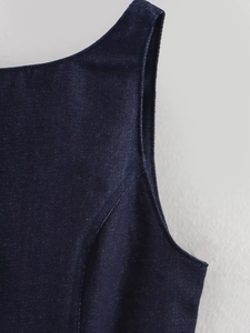 Gros plan détaillé montrant la texture du denim bleu foncé et les coutures du haut sans manches