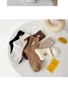 Chaussettes brodées aux tons terreux beige et café présentées sur une table minimaliste