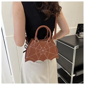 Detailed view of brown bat-wing crossbody bag with white spiderweb stitching and strap