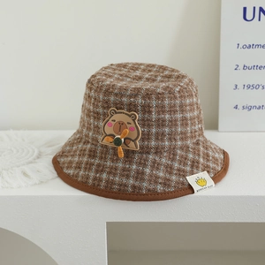Détail du chapeau cloche à carreaux pour enfant avec écusson capybara et hélice