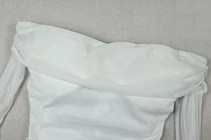 Detail of white mesh dress showing the off-shoulder neckline and pleated sheer fabric