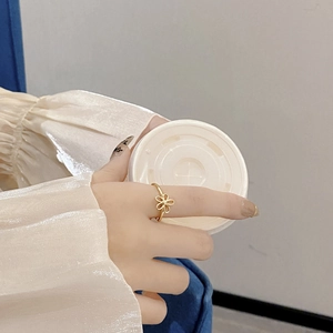 Detail of a minimalist gold hollow flower open ring worn on a woman finger