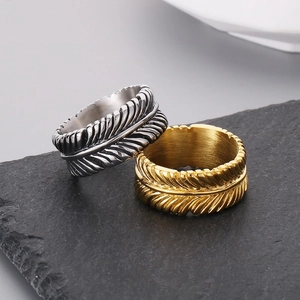 Minimalist feather design stainless steel rings in silver and gold on a stone base